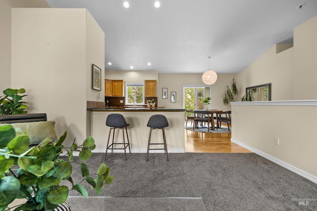 5873 N Collister Dr, Boise, ID 83703 - kitchen with light carpet, a kitchen breakfast bar, recessed lighting, dark countertops, and a peninsula