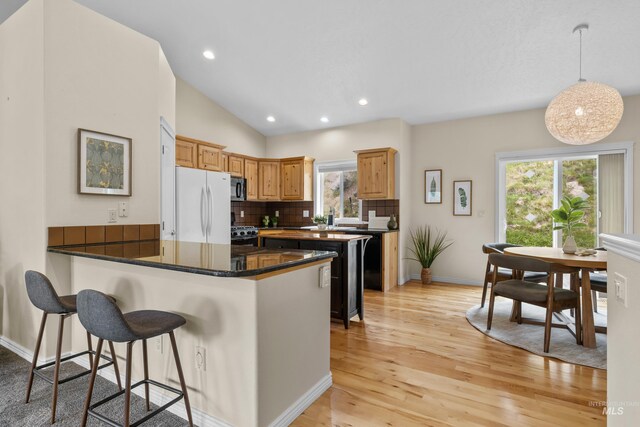 5873 N Collister Dr, Boise, ID 83703 - kitchen featuring freestanding refrigerator, black microwave, baseboards, light wood-style flooring, and tasteful backsplash