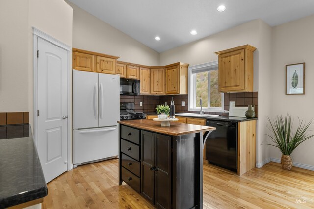 5873 N Collister Dr, Boise, ID 83703 - kitchen featuring black appliances, dark countertops, decorative backsplash, light wood finished floors, and vaulted ceiling