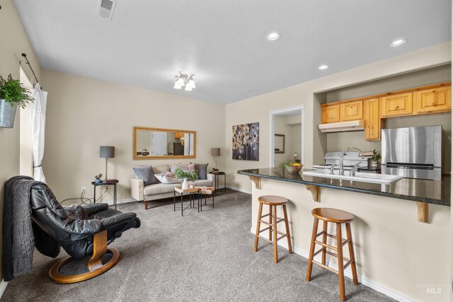5873 N Collister Dr, Boise, ID 83703 - kitchen with freestanding refrigerator, a breakfast bar area, under cabinet range hood, open floor plan, and recessed lighting