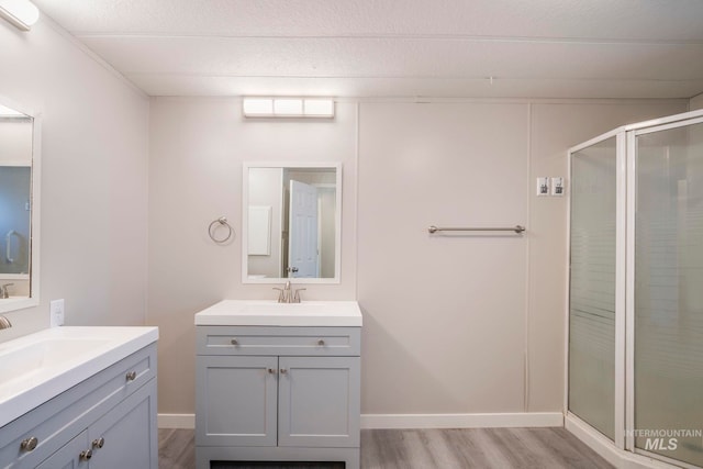 347 Winona Dr, Fairfield, ID 83327 - full bathroom featuring a sink, two vanities, a shower stall, and wood finished floors