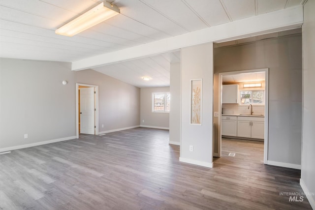 347 Winona Dr, Fairfield, ID 83327 - unfurnished living room featuring a sink, baseboards, wood finished floors, and lofted ceiling with beams