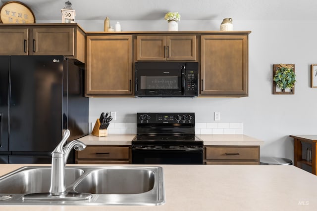 kitchen with light countertops, brown cabinets, a sink, and black appliances