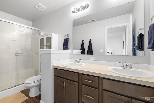 full bath with toilet, visible vents, a shower stall, and a sink