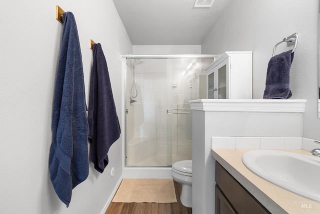 full bathroom with vanity, toilet, baseboards, wood finished floors, and a stall shower