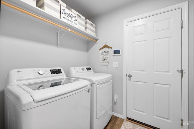 washroom featuring laundry area, baseboards, independent washer and dryer, and wood finished floors