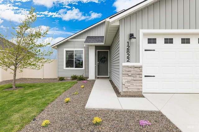 entrance to property featuring a garage, fence, board and batten siding, and a yard