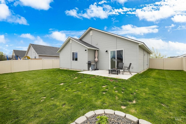 rear view of house with a fenced backyard, a yard, and a patio area