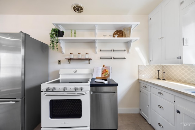 kitchen featuring visible vents, backsplash, freestanding refrigerator, white cabinets, and white electric stove