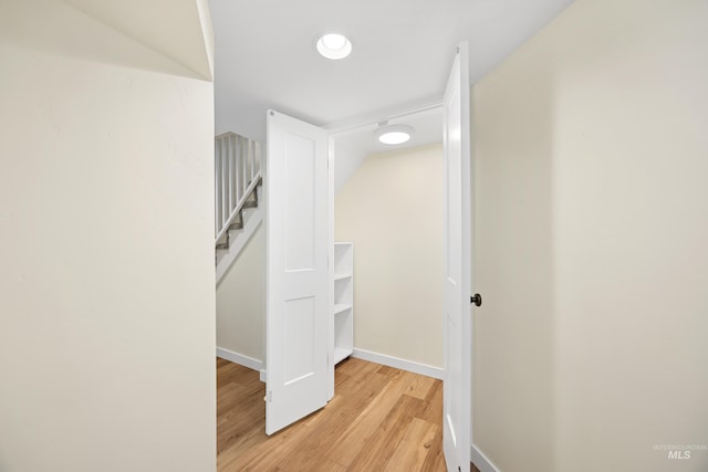 corridor with stairway, baseboards, and light wood-style floors