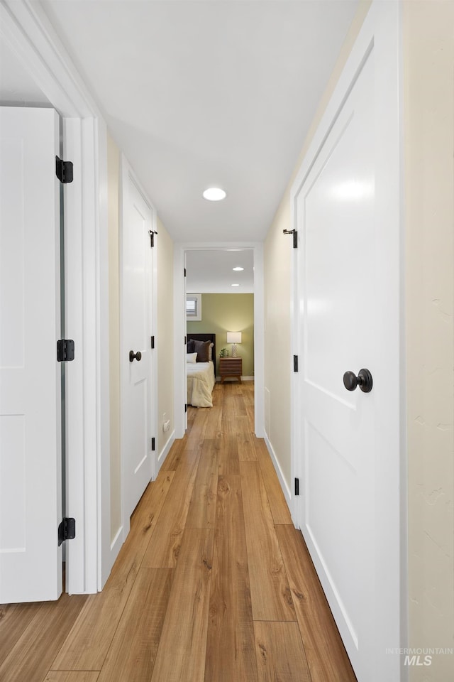 hall featuring baseboards and light wood-type flooring