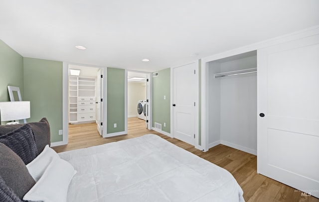 bedroom featuring washer and dryer, a closet, baseboards, and wood finished floors