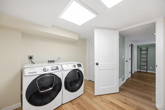 laundry room featuring baseboards, independent washer and dryer, light wood-style flooring, and laundry area