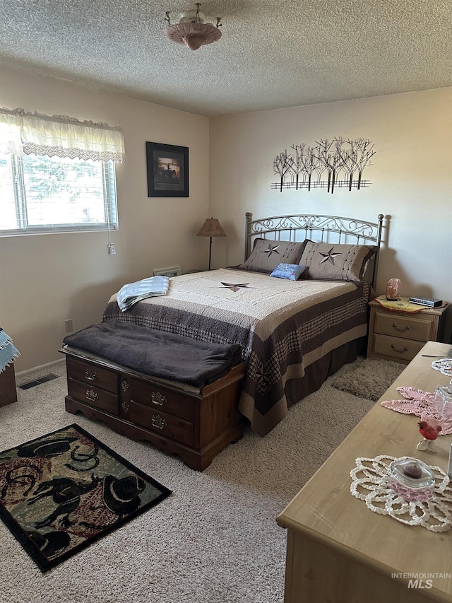 bedroom with visible vents, a textured ceiling, and carpet