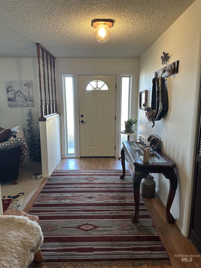 foyer entrance featuring wood finished floors, baseboards, and a textured ceiling