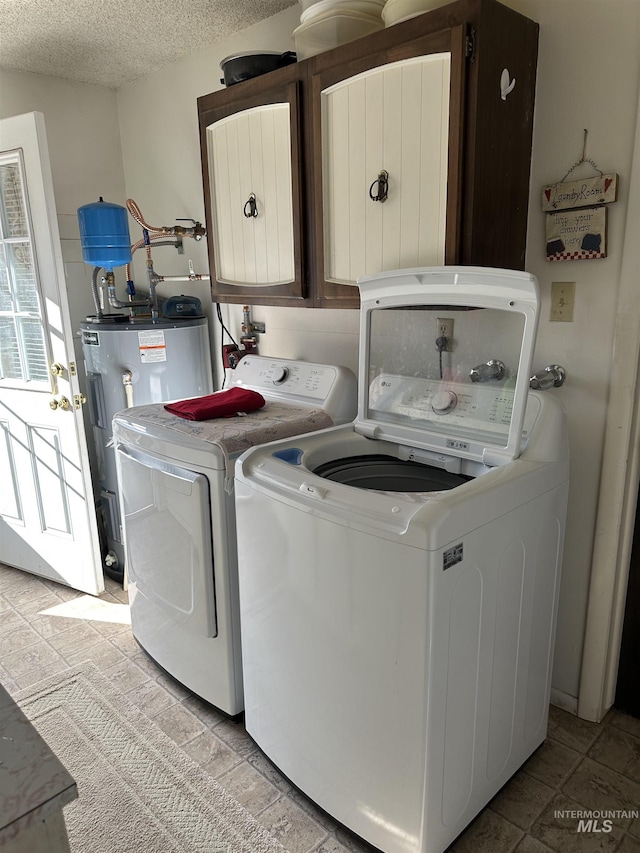 laundry room with cabinet space, electric water heater, washing machine and dryer, and a textured ceiling