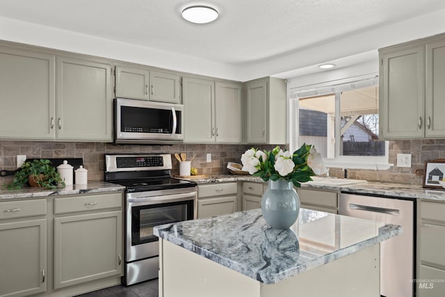 kitchen featuring light stone counters, decorative backsplash, a kitchen island, and stainless steel appliances