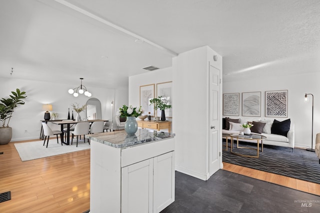 kitchen featuring a center island, open floor plan, dark wood-style floors, arched walkways, and white cabinets