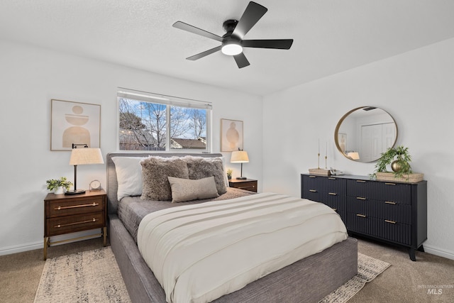 bedroom with light colored carpet, a textured ceiling, baseboards, and ceiling fan