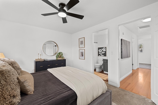 bedroom featuring visible vents, connected bathroom, baseboards, light colored carpet, and ceiling fan