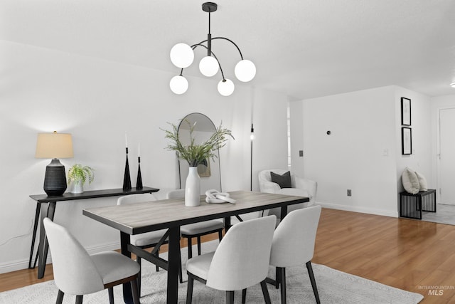 dining room with baseboards, an inviting chandelier, and wood finished floors