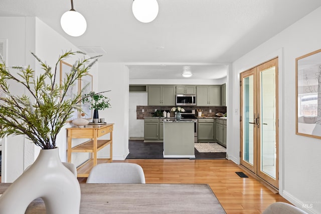 interior space with visible vents, baseboards, french doors, and light wood finished floors