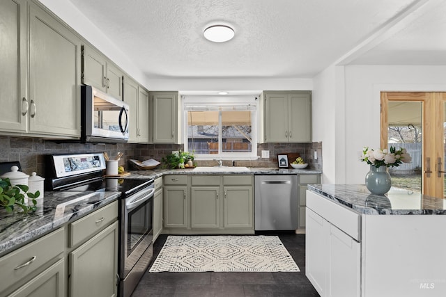 kitchen featuring backsplash, appliances with stainless steel finishes, stone countertops, a textured ceiling, and a sink