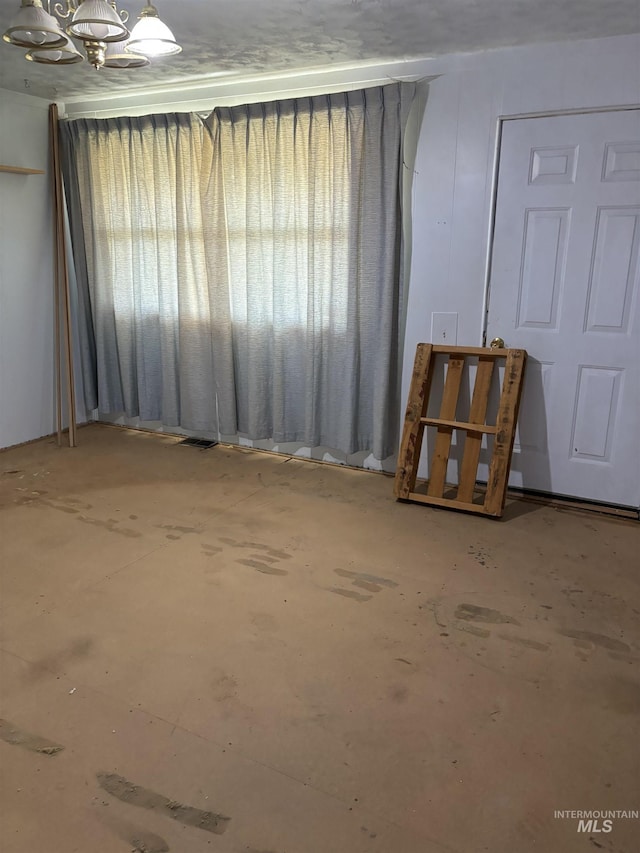 empty room featuring concrete flooring and a notable chandelier