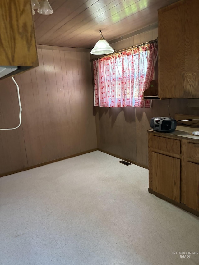 interior space with hanging light fixtures, light carpet, wooden ceiling, and wood walls