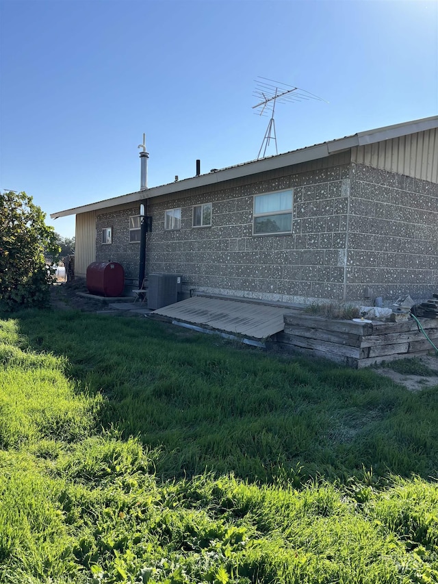 rear view of house featuring cooling unit and a lawn