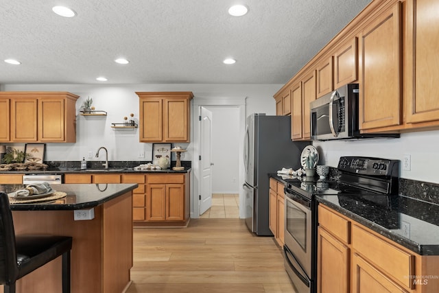 kitchen featuring a sink, appliances with stainless steel finishes, a textured ceiling, recessed lighting, and light wood-style flooring