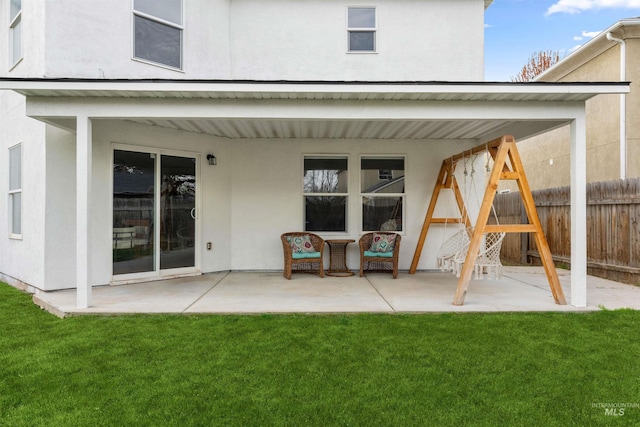 back of house featuring a patio area, stucco siding, fence, and a lawn