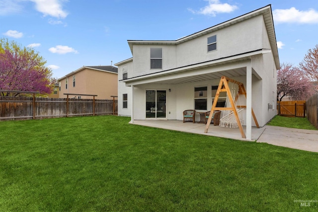 rear view of property with a patio area, a yard, a fenced backyard, and stucco siding