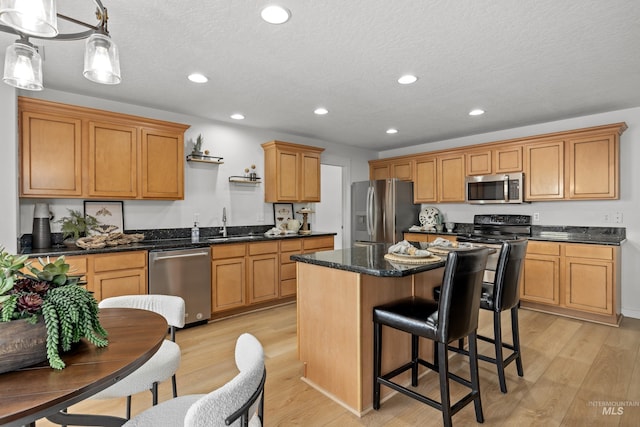 kitchen featuring light wood-type flooring, a kitchen island, recessed lighting, a sink, and stainless steel appliances