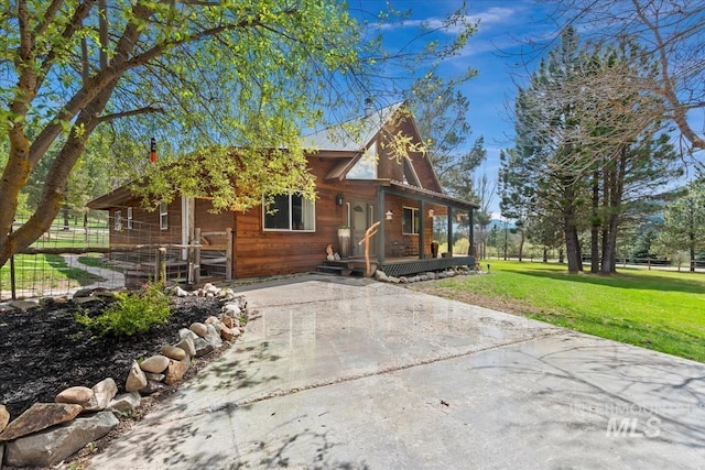 view of front of property with covered porch, fence, driveway, and a front yard