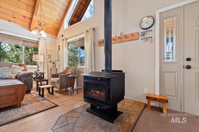 living room featuring a wood stove, wood finished floors, beam ceiling, high vaulted ceiling, and wood ceiling