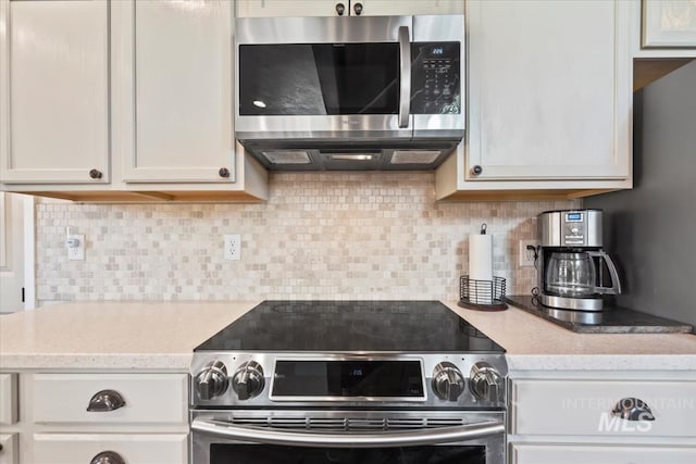 kitchen featuring white cabinets, light stone countertops, appliances with stainless steel finishes, and decorative backsplash