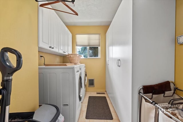 clothes washing area featuring light tile patterned floors, washing machine and dryer, cabinet space, and visible vents