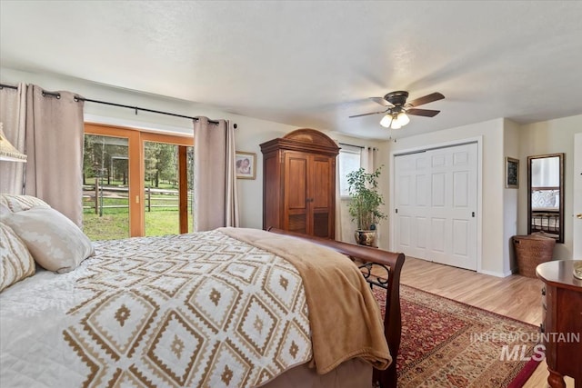 bedroom featuring a ceiling fan, access to exterior, wood finished floors, and multiple windows