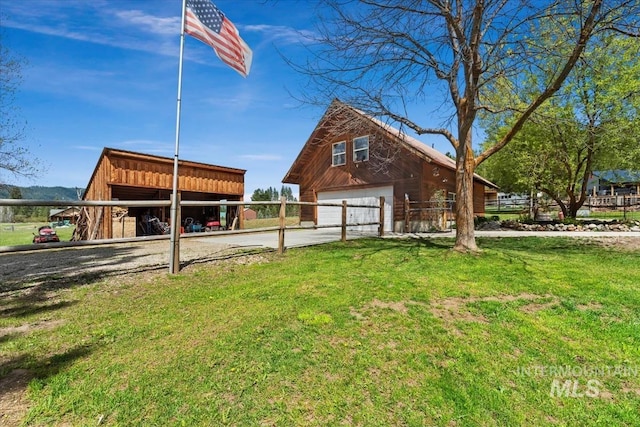 chalet / cabin with a garage, fence, a front yard, an outbuilding, and driveway