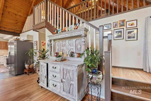 interior space featuring light wood-style floors, high vaulted ceiling, stainless steel fridge, light countertops, and wood ceiling