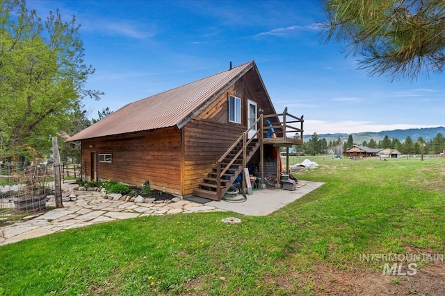 view of property exterior featuring stairs, a lawn, a deck with mountain view, and metal roof