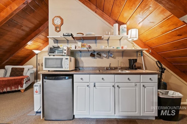 kitchen featuring carpet, freestanding refrigerator, vaulted ceiling with beams, white microwave, and wood ceiling