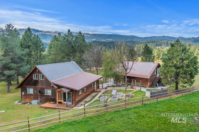 exterior space with a yard, a deck with mountain view, a wooded view, and a fenced backyard