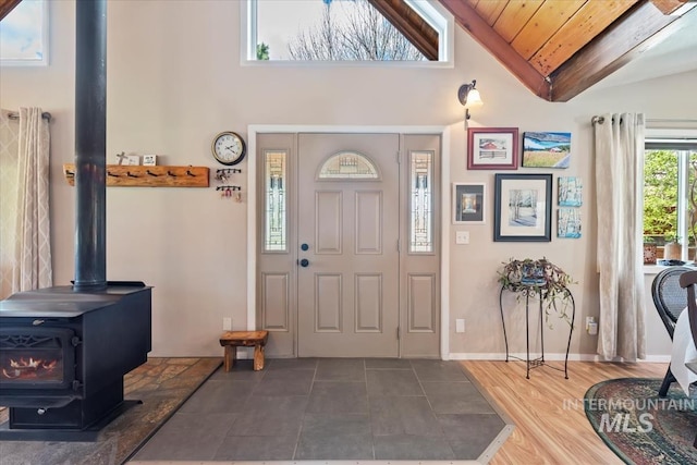 entryway with baseboards, a wood stove, wood ceiling, and high vaulted ceiling