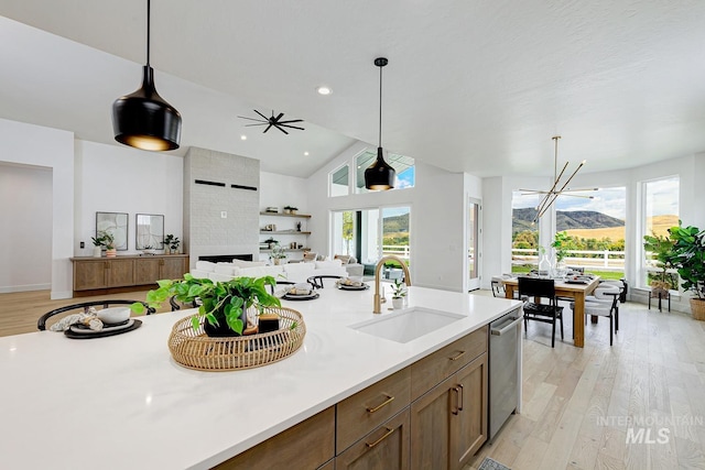 kitchen featuring hanging light fixtures, light wood-style floors, light countertops, a sink, and open floor plan