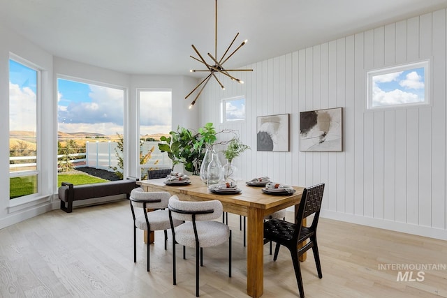 dining area with an inviting chandelier, light wood-style flooring, and baseboards