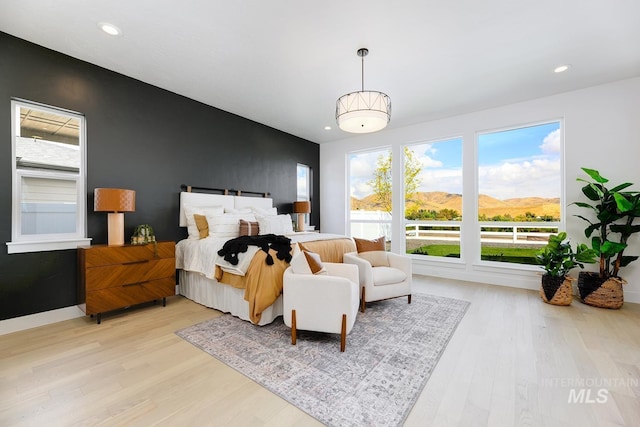 bedroom featuring light wood finished floors, recessed lighting, baseboards, and a mountain view