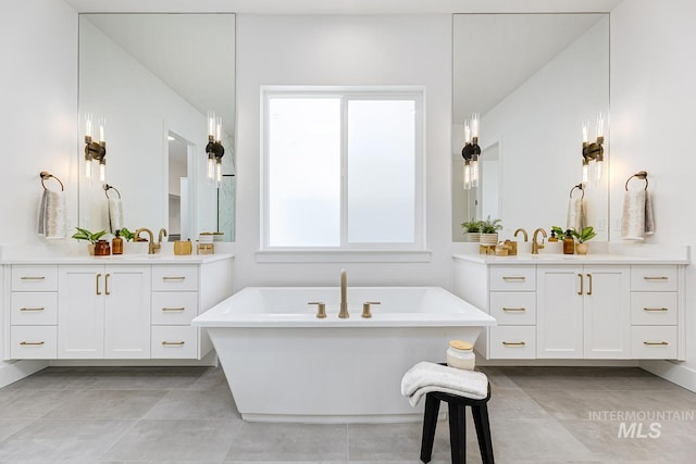 full bath with two vanities, a freestanding tub, and tile patterned floors