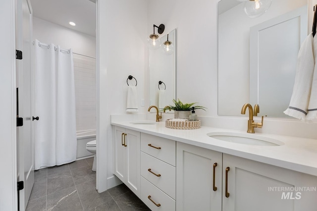 bathroom featuring shower / bath combo, toilet, double vanity, and a sink